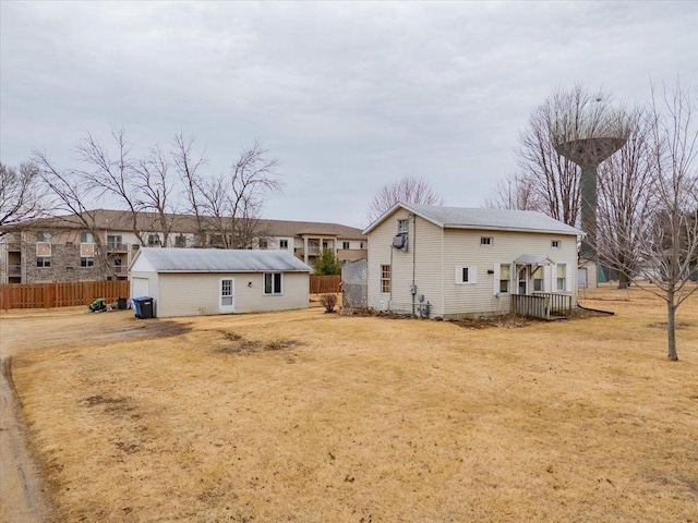 view of front facade with an outbuilding, fence, and a front lawn