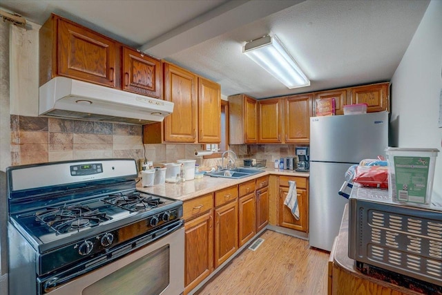 kitchen with tasteful backsplash, appliances with stainless steel finishes, a sink, and under cabinet range hood