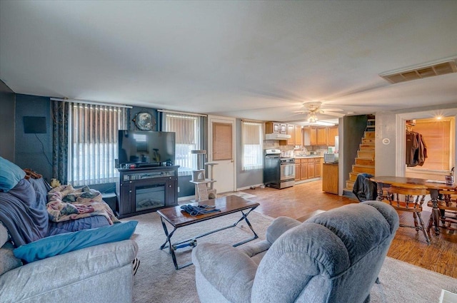 living area with stairs, visible vents, a fireplace, and a wealth of natural light