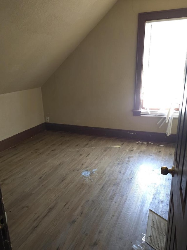 additional living space with lofted ceiling, baseboards, and wood finished floors