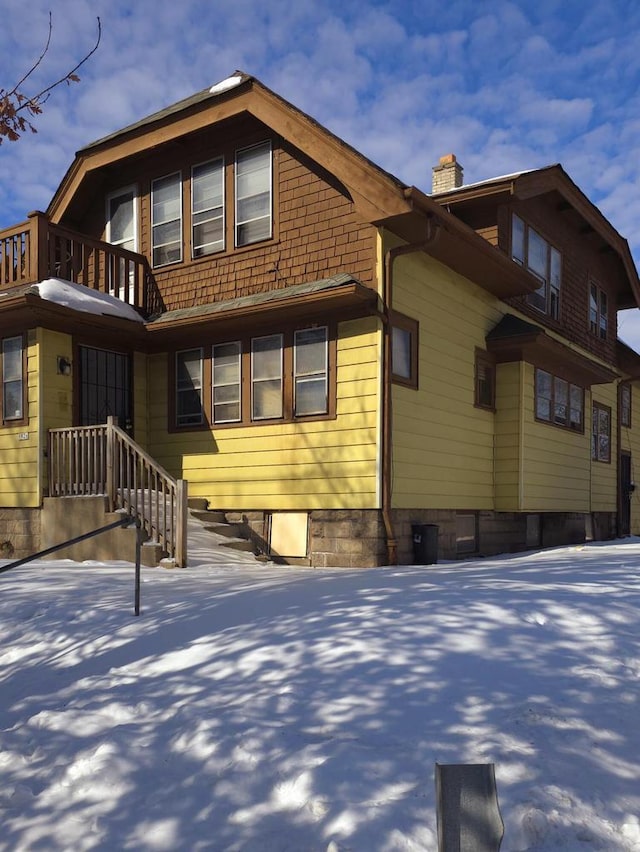 view of snow covered exterior with a chimney and a balcony