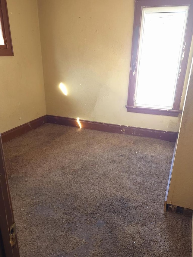 carpeted spare room featuring baseboards