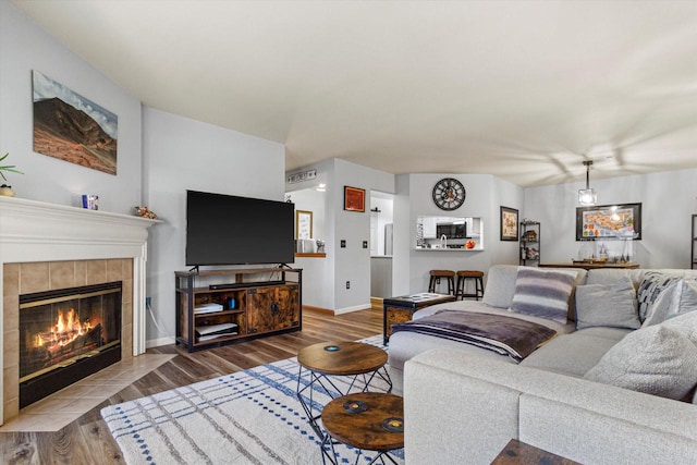 living room with a fireplace, baseboards, and wood finished floors