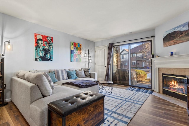 living room featuring a tiled fireplace and wood finished floors