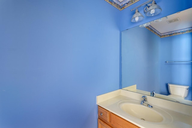 bathroom with toilet, vanity, and visible vents