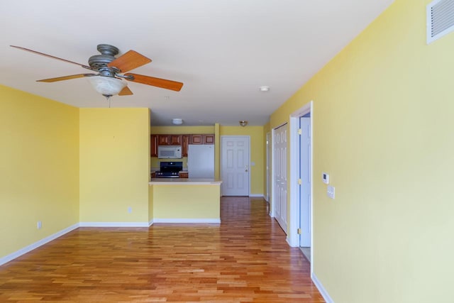 unfurnished living room with a ceiling fan, light wood-type flooring, visible vents, and baseboards