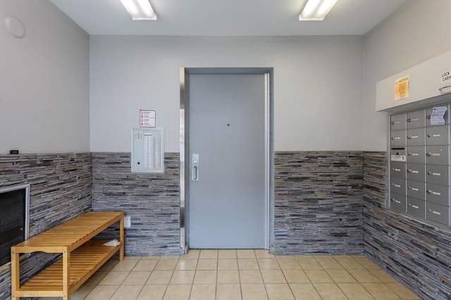 interior space featuring a wainscoted wall, mail area, tile patterned flooring, and tile walls