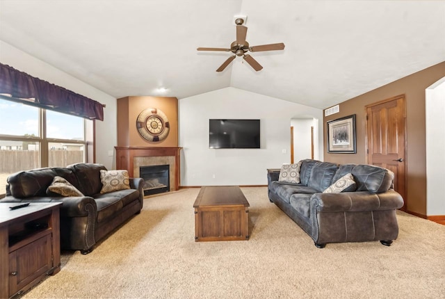 living room featuring baseboards, a tiled fireplace, light colored carpet, ceiling fan, and vaulted ceiling