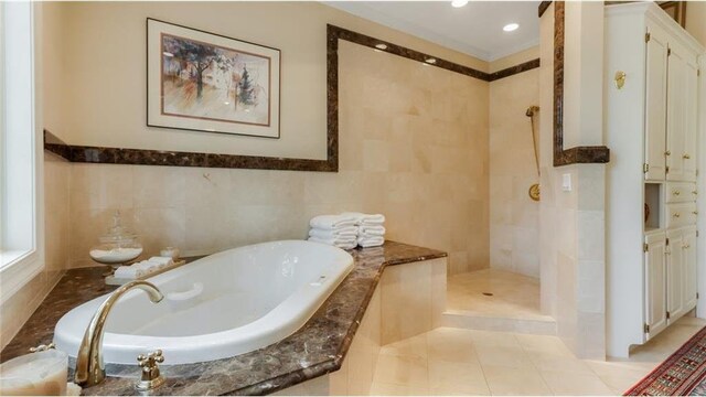 bathroom featuring a garden tub, tile patterned floors, tile walls, and a walk in shower