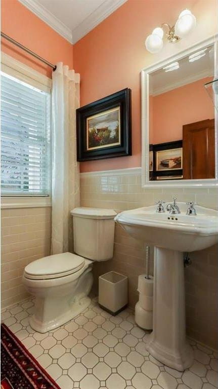 bathroom featuring tile walls, toilet, a wainscoted wall, and ornamental molding