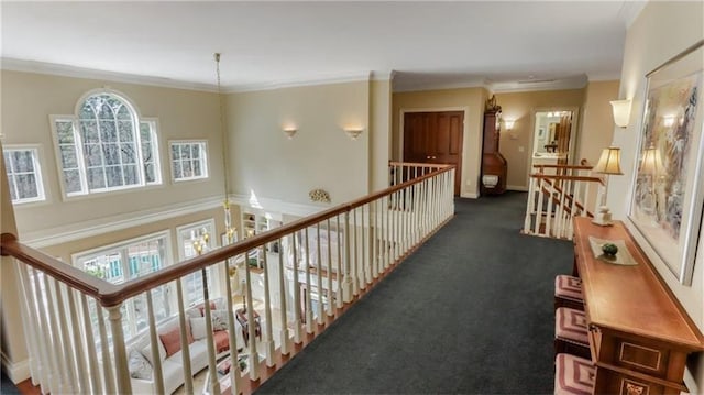 hall featuring baseboards, an upstairs landing, dark colored carpet, and ornamental molding