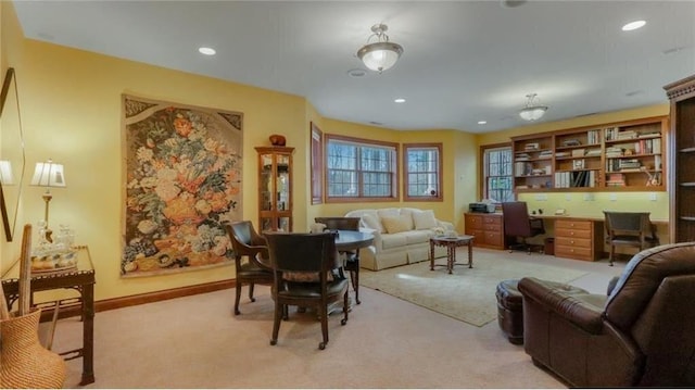 living area with baseboards, recessed lighting, built in desk, and light carpet