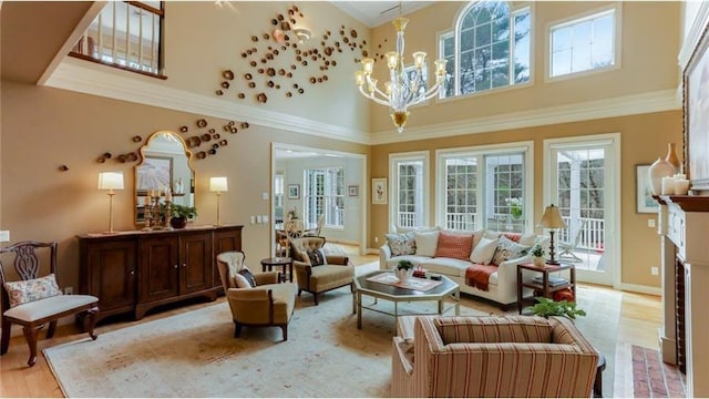 living area with baseboards, a high ceiling, crown molding, a notable chandelier, and light wood-type flooring