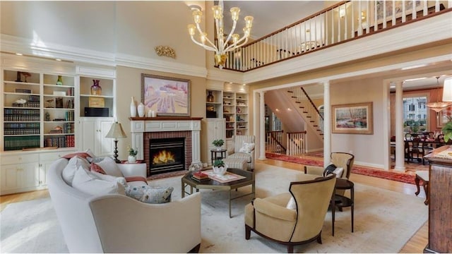 living area featuring stairs, a brick fireplace, built in features, and wood finished floors