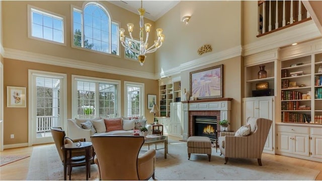 sitting room featuring a wealth of natural light, light wood-style floors, a brick fireplace, and a chandelier