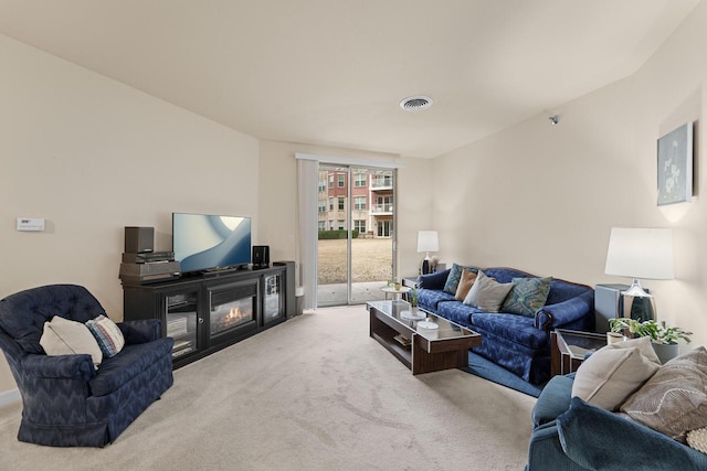 living room with carpet floors, a glass covered fireplace, and visible vents