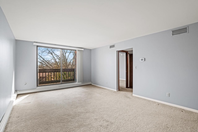 unfurnished room featuring visible vents, carpet flooring, a baseboard heating unit, and baseboards