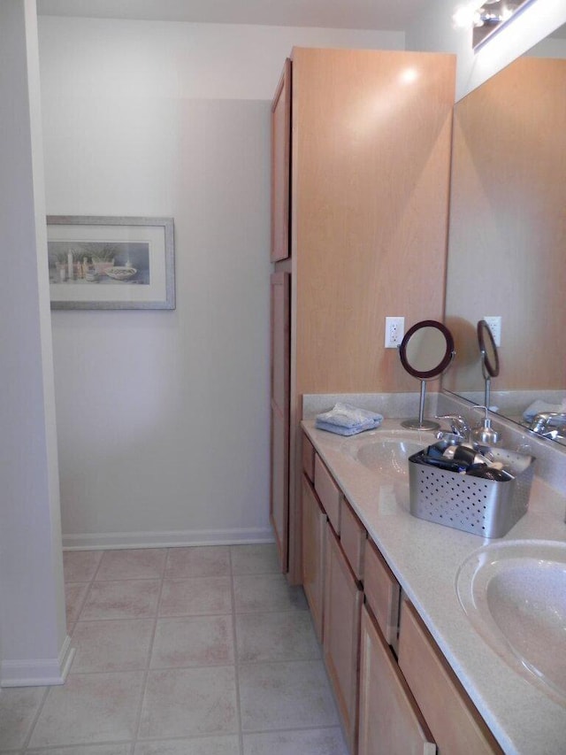 full bath featuring double vanity, a sink, and baseboards