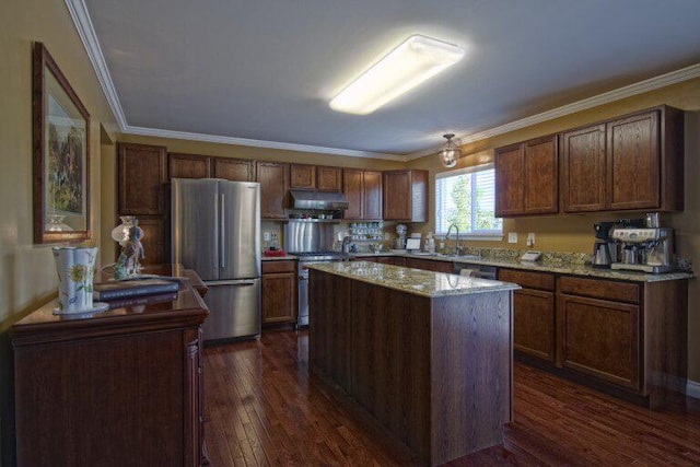 kitchen featuring under cabinet range hood, stainless steel appliances, dark wood-style flooring, a sink, and crown molding