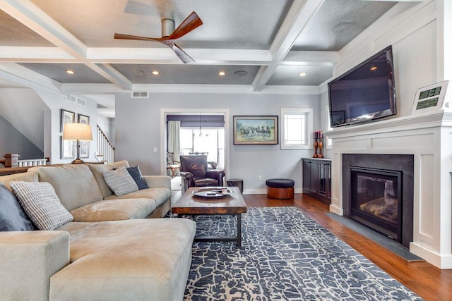 living area with visible vents, coffered ceiling, a fireplace with flush hearth, stairway, and wood finished floors