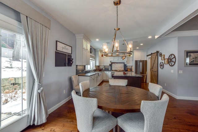 dining area featuring a barn door, baseboards, and wood finished floors