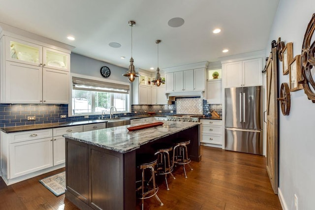 kitchen featuring dark wood-style floors, a center island, a kitchen bar, and freestanding refrigerator