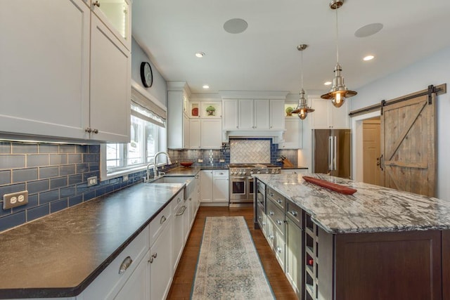 kitchen featuring a barn door, tasteful backsplash, high quality appliances, a center island, and white cabinetry