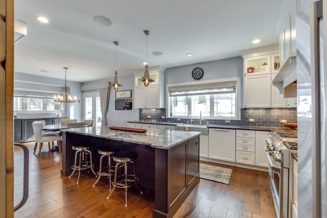 kitchen with range with two ovens, dark wood finished floors, white dishwasher, a sink, and a kitchen island