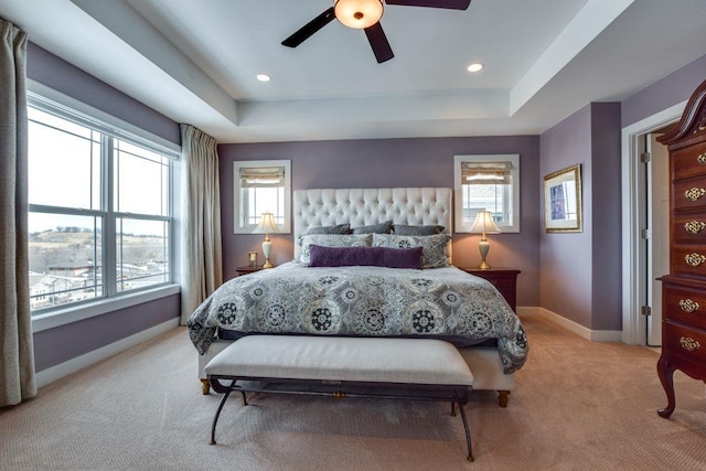 bedroom featuring ceiling fan, recessed lighting, light colored carpet, baseboards, and a raised ceiling