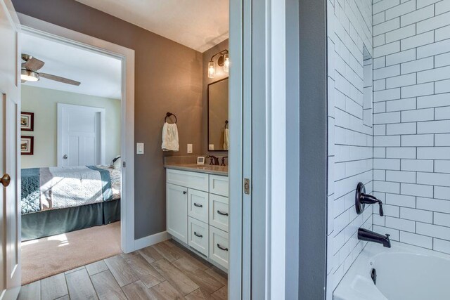 bathroom with wood tiled floor, connected bathroom, vanity,  shower combination, and baseboards