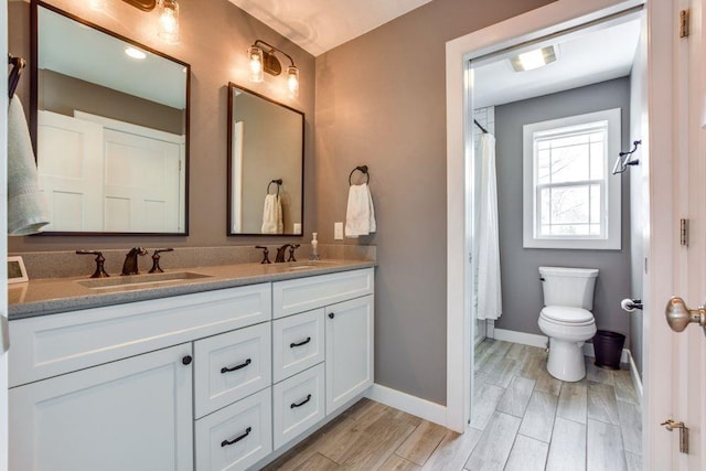 bathroom featuring double vanity, wood tiled floor, baseboards, and a sink