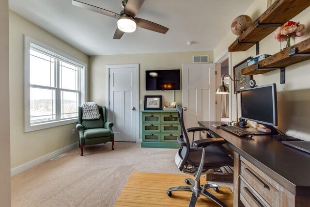 office area featuring baseboards, visible vents, a ceiling fan, and light colored carpet