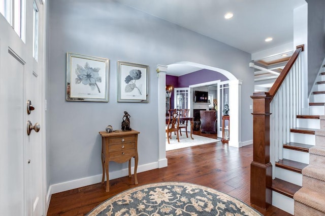 entryway with arched walkways, recessed lighting, stairway, wood finished floors, and baseboards