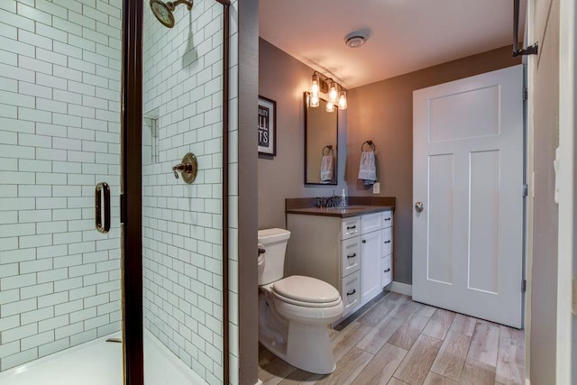 full bathroom featuring wood finished floors, a stall shower, vanity, and toilet