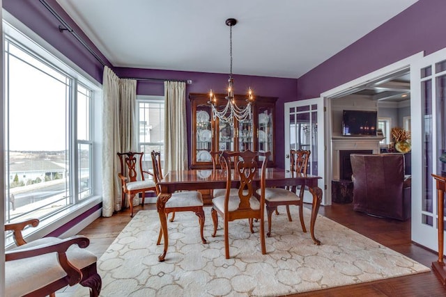 dining area featuring wood finished floors, a fireplace, and an inviting chandelier