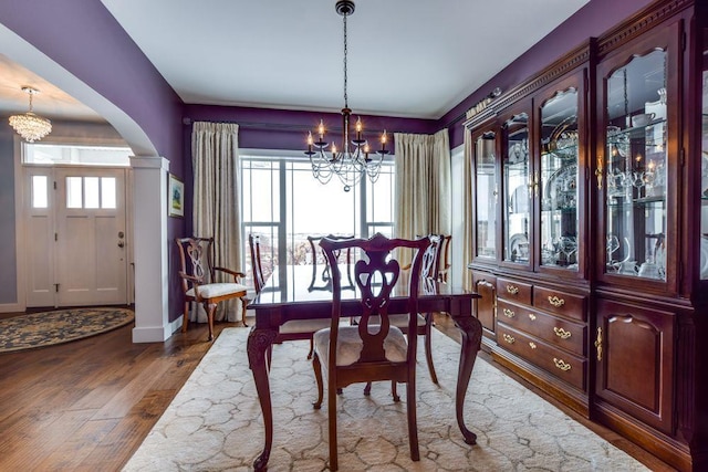 dining area with a wealth of natural light, wood finished floors, and an inviting chandelier