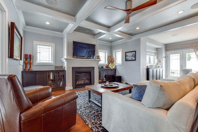 living area featuring a large fireplace, french doors, beam ceiling, and a wealth of natural light