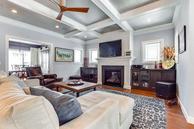 living area featuring beam ceiling, a glass covered fireplace, wood finished floors, coffered ceiling, and baseboards