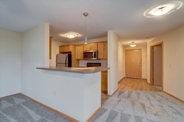 kitchen featuring light carpet, baseboards, appliances with stainless steel finishes, a peninsula, and light countertops