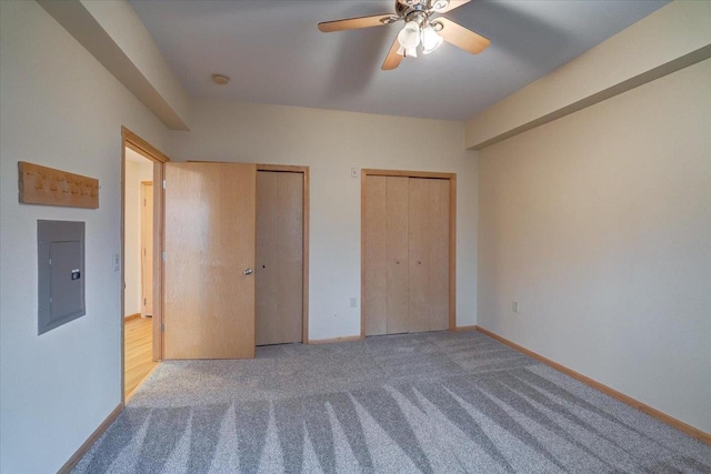 unfurnished bedroom featuring carpet, two closets, electric panel, and baseboards