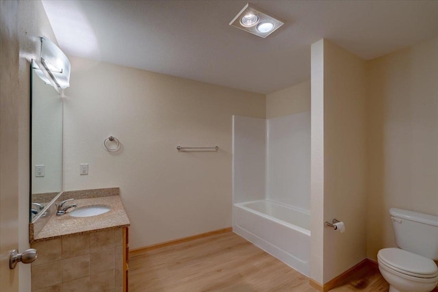 bathroom featuring toilet, baseboards, wood finished floors, and vanity