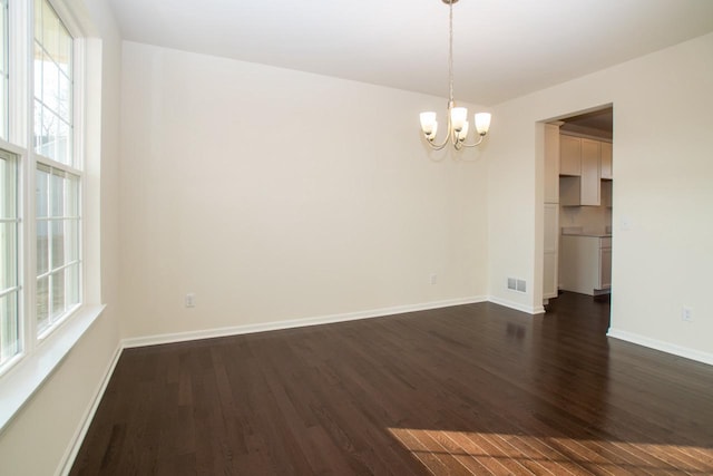 unfurnished room with visible vents, dark wood-style flooring, a wealth of natural light, and baseboards