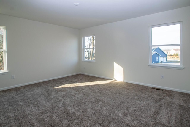 carpeted spare room with visible vents and baseboards