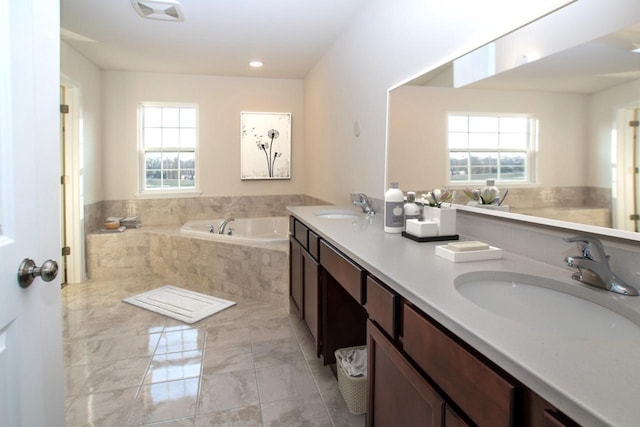 bathroom with visible vents, double vanity, a sink, and a bath