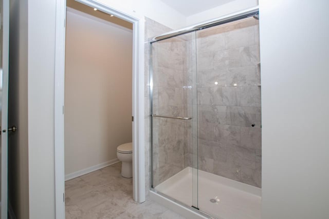 bathroom featuring baseboards, a shower stall, and toilet