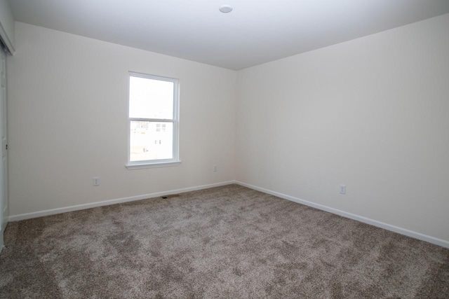 spare room with carpet flooring, visible vents, and baseboards