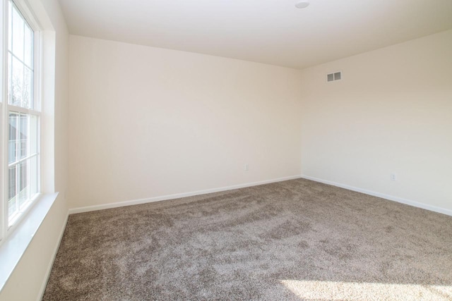 spare room with carpet, visible vents, and baseboards