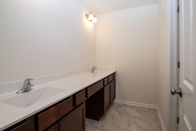 bathroom featuring double vanity, tile patterned flooring, a sink, and baseboards