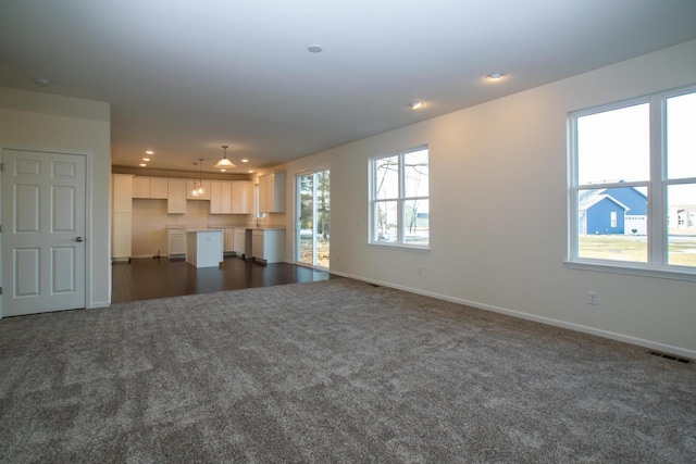 unfurnished living room featuring baseboards, visible vents, dark colored carpet, and recessed lighting