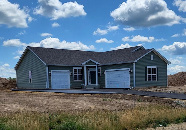 ranch-style house with a garage and a shingled roof